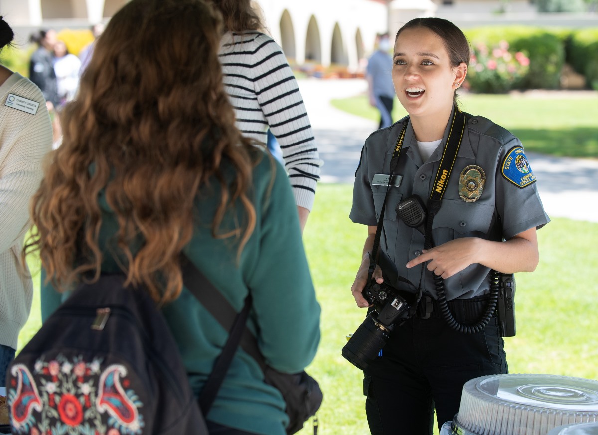 A female police officer in uniform speaks with a Cal Poly Pomona student during Pastries with Public Safety event