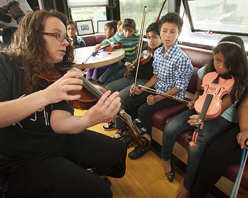Professor Jennfer Amaya gives violin pointers to elementary school students