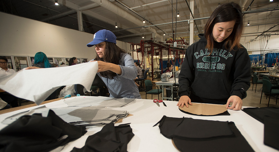 Two students form a production line and measure clothing