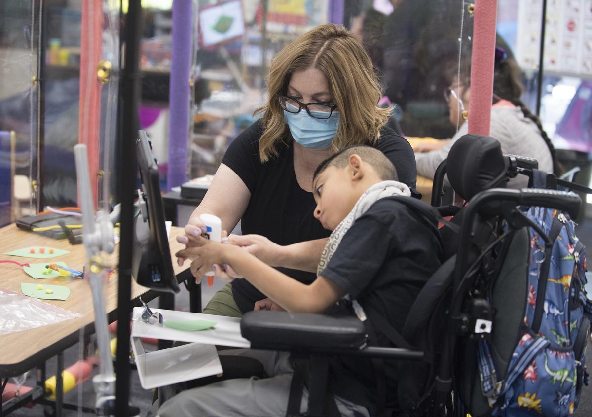 A special ed teacher works with a child on an art project.