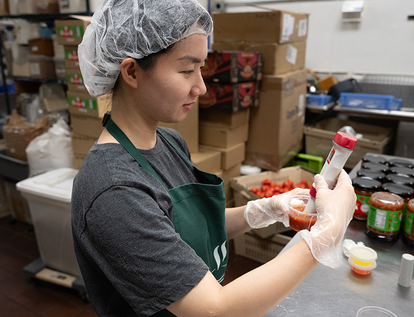 Female student works with ingredients to create Salsa.