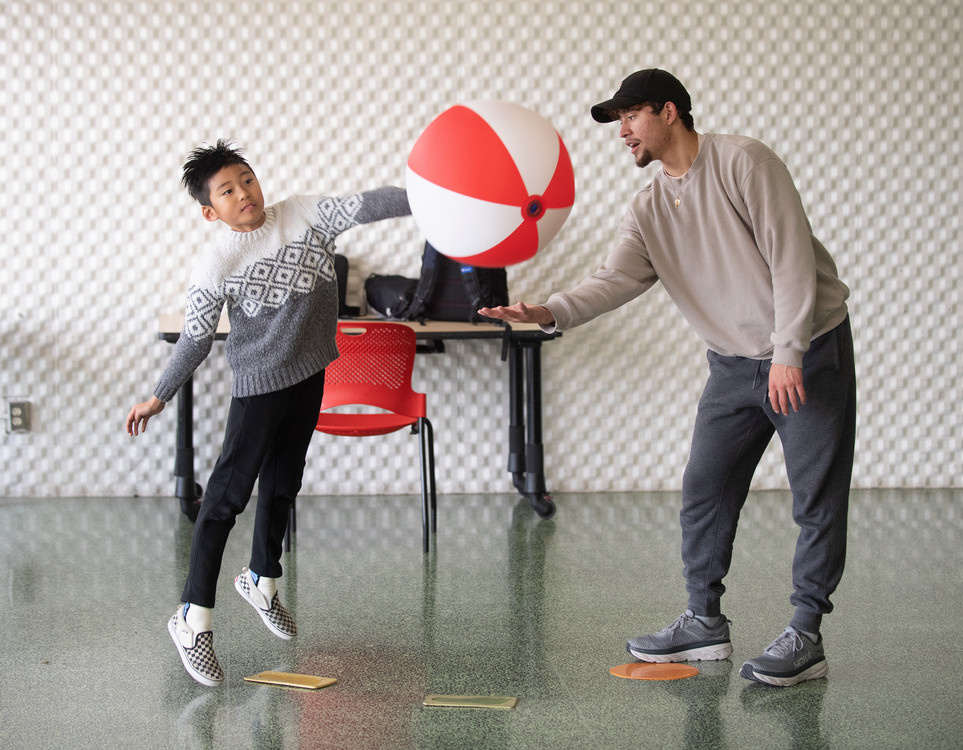 student helping child play with ball