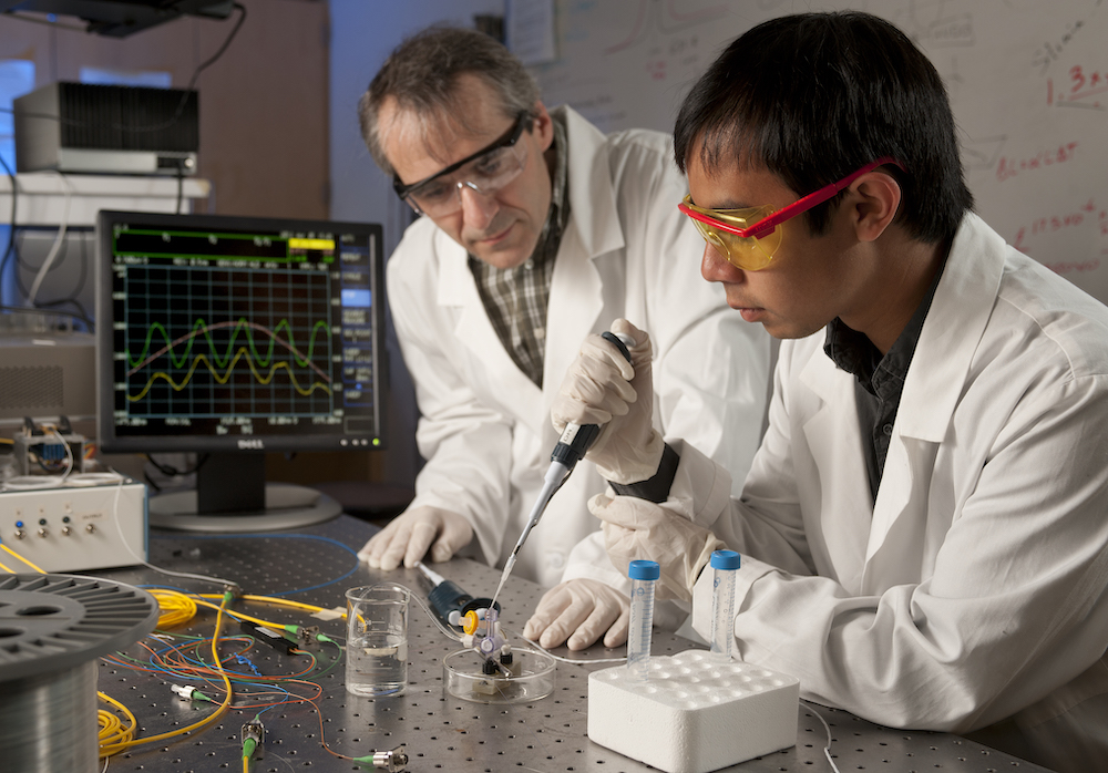 Ertan Salik watches a student conduct an experiment in the lab