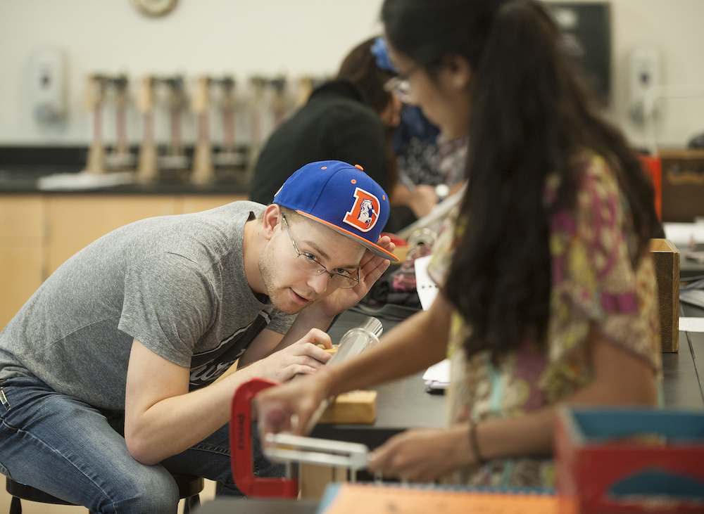 students listen at the end of a metal tube for an experiment on the speed of sound