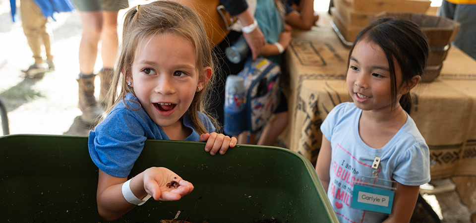 A girl has a surprised expression while handling worms