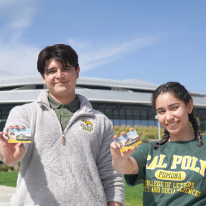 Two students holding up their student ID cards