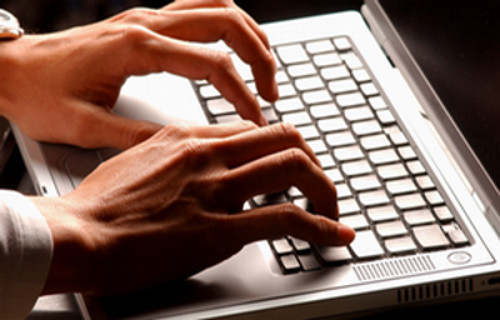 A person's hands typing on a laptop