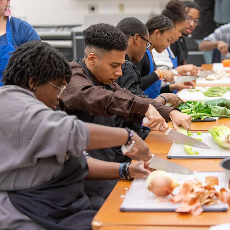Students chop produce as they make gumbo as part of Black History Month experience.
