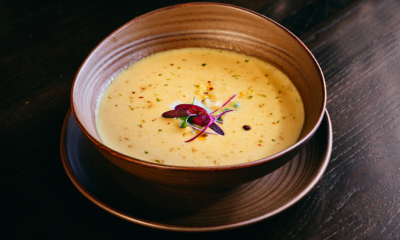 Roasted yellow corn soup close-up in a wooden bowl on a table.