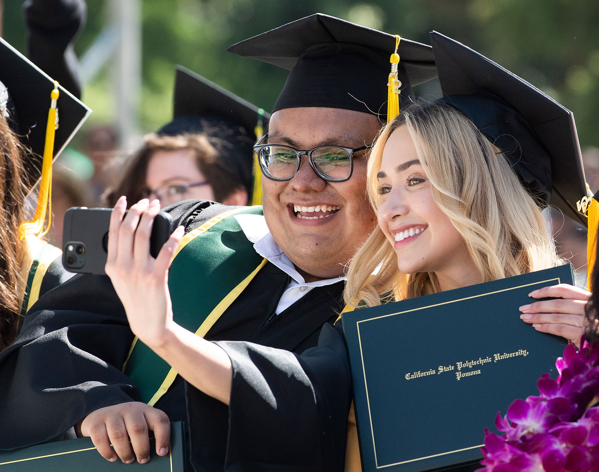 two graduating students pose for a selfie.