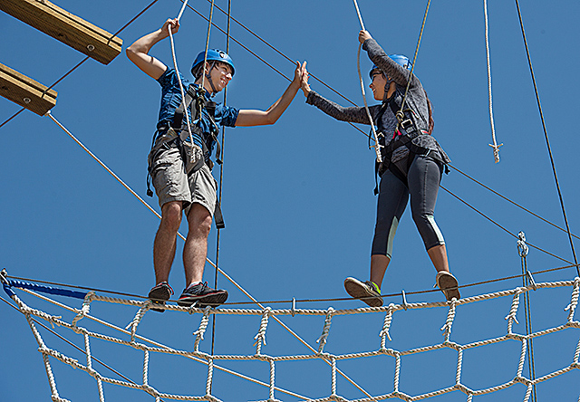 Two students in rope-climbing gear participate in a Challenge Ropes Course activity class offered by the Kinesiology department
