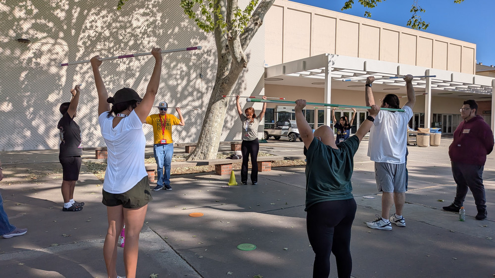 Group of people doing shoulder press using PVC pipe