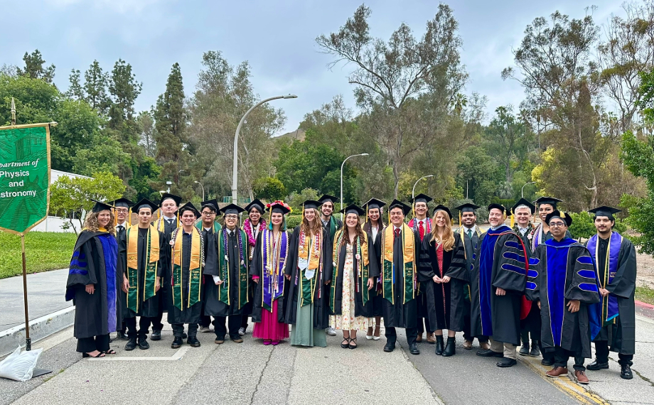 the physics and astronomy graduating students stand next to faculty on graduation day outside of building 1