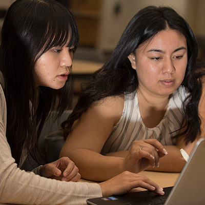 Two female students working on laptops
