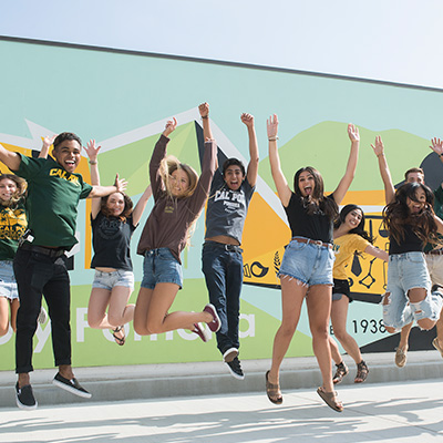 A group of students jumping in front of a mural