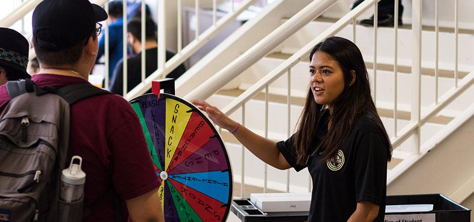 A Student Success Ambassador talks to two students at tabling event. 