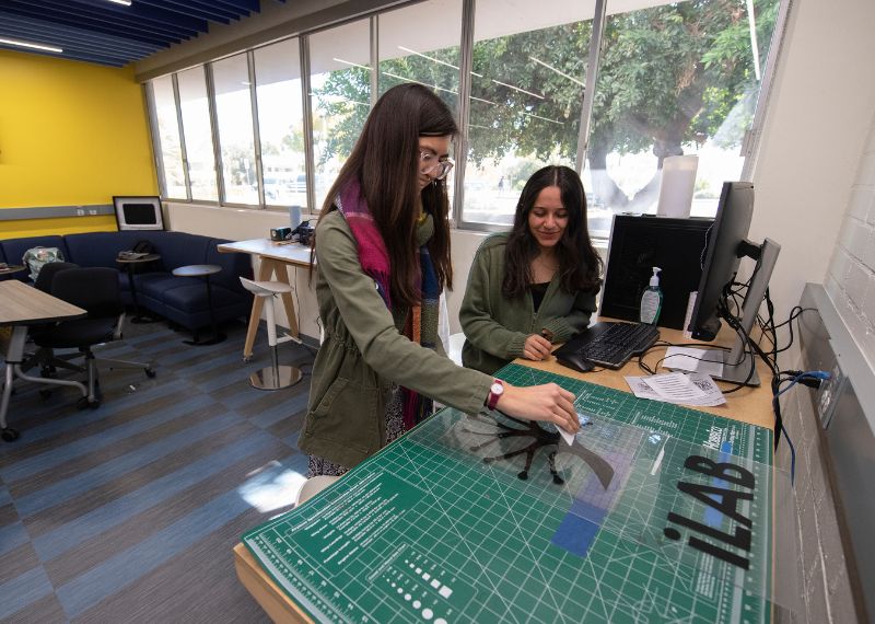 SIILL Student showing student how to use a machine.