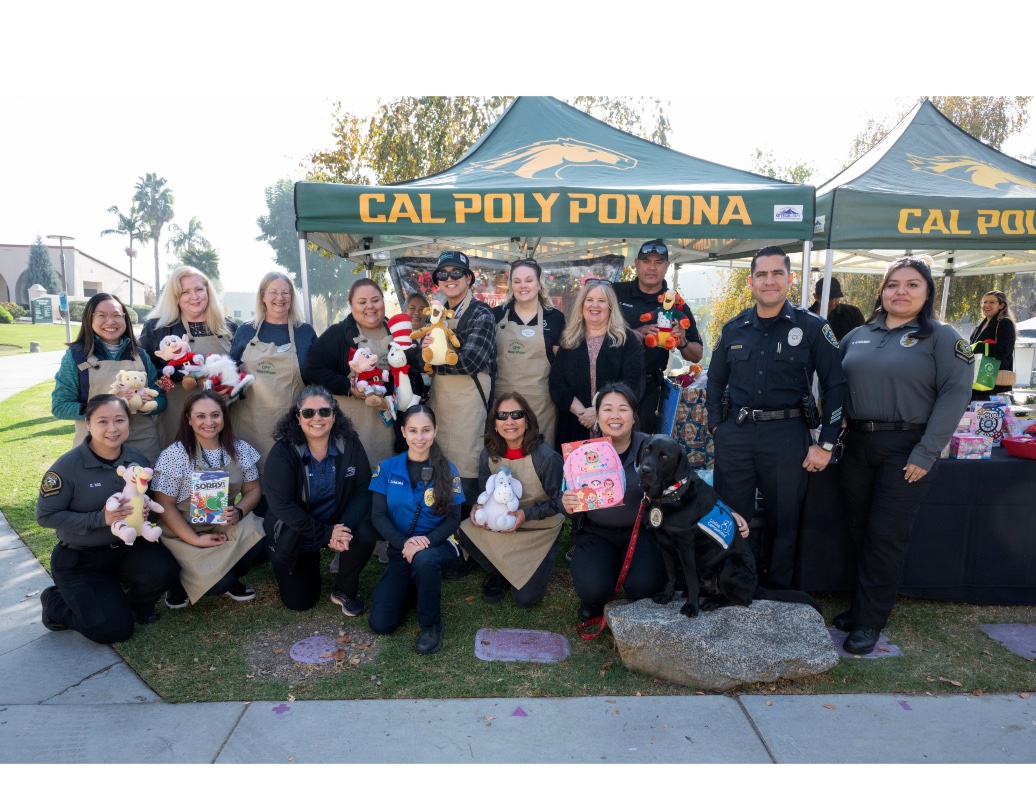 Group photo of staff and police office from Pomona PD. They are all holding different toy and smiling. 