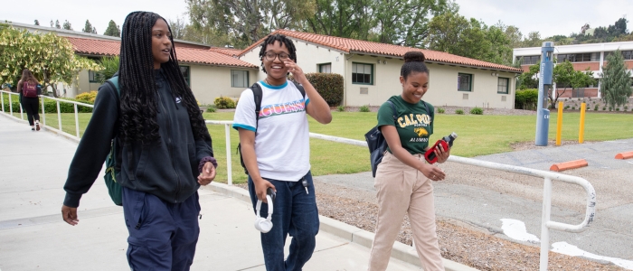 3 students walk together on campus