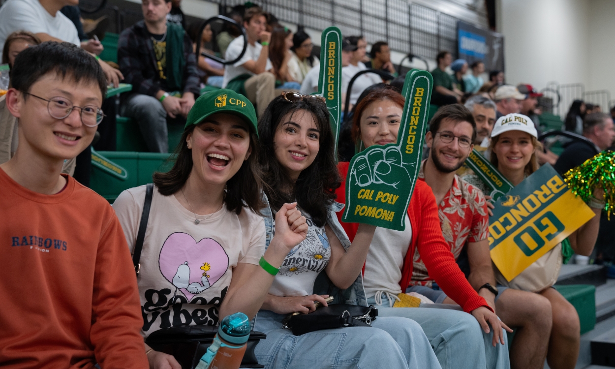 Students decked out in CPP gear cheer on the basketball team at a game.