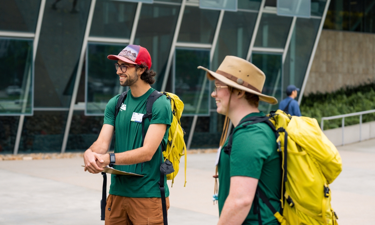 Two hiking staff members listen to a student