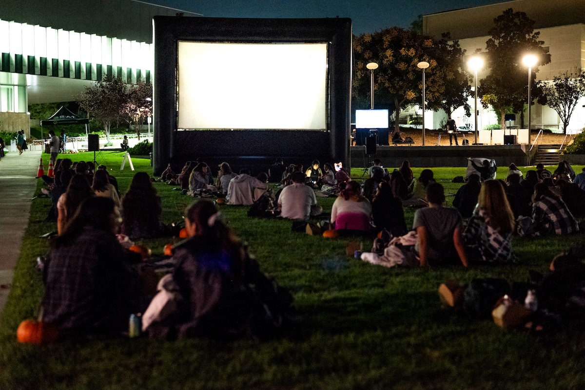 Students watch a movie on the lawn