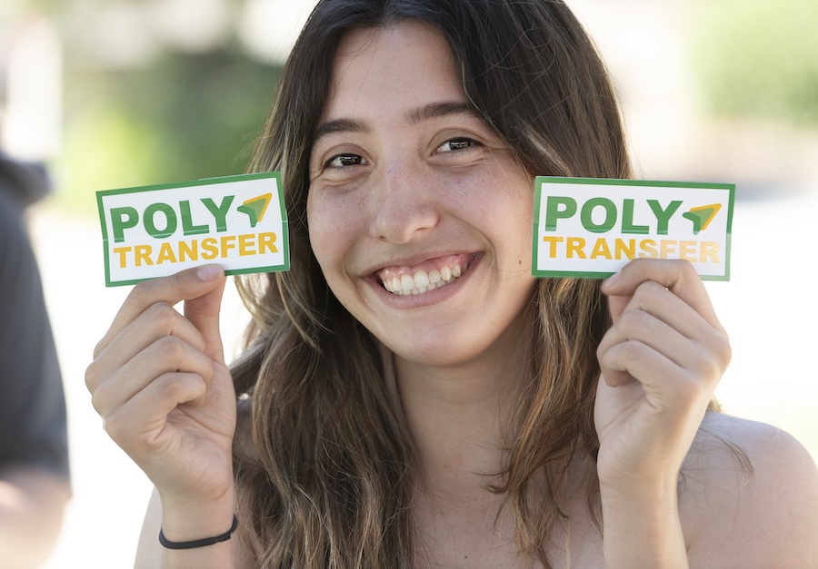A transfer student holds up stickers that say PolyTransfer