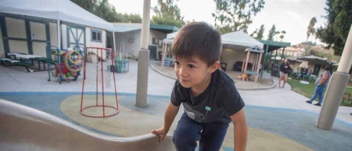A child at the Children's Center climbs up a slide