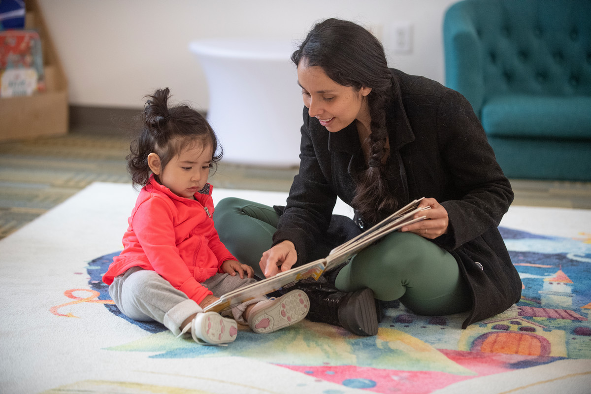 A parent reads to her student at the University Library
