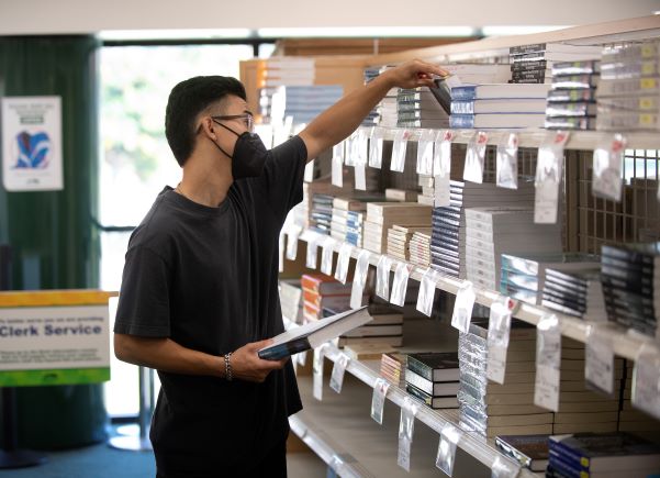Student in bookstore grabbing textbooks