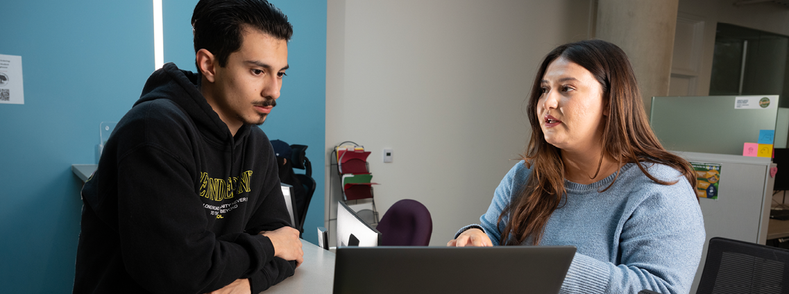 An advisor works with a student at the counter