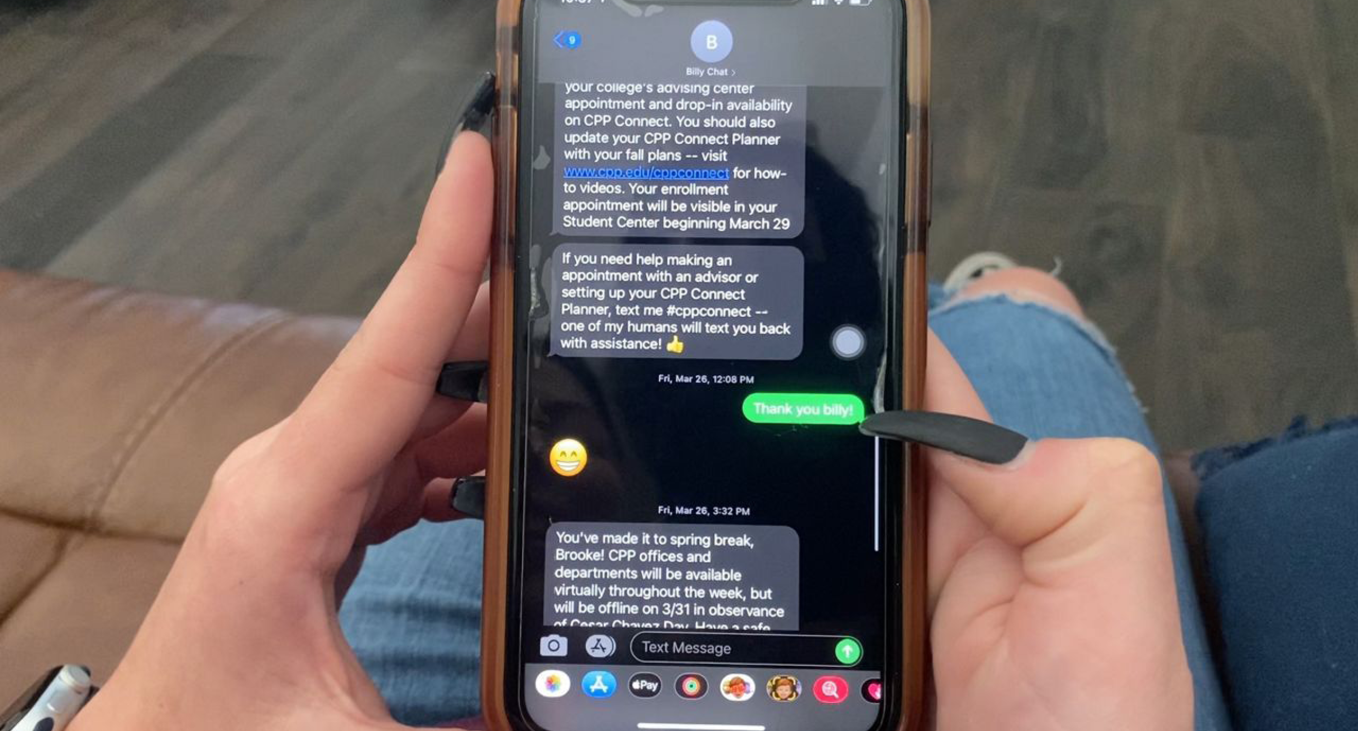 A student holds their phone that's showing text messages from Billy Chat