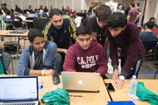 A group of 5 male students looking at a laptop
