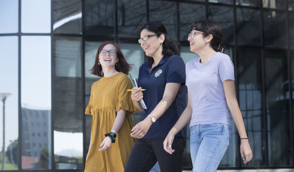 Two students and an advisor walk together in the Student Services Building