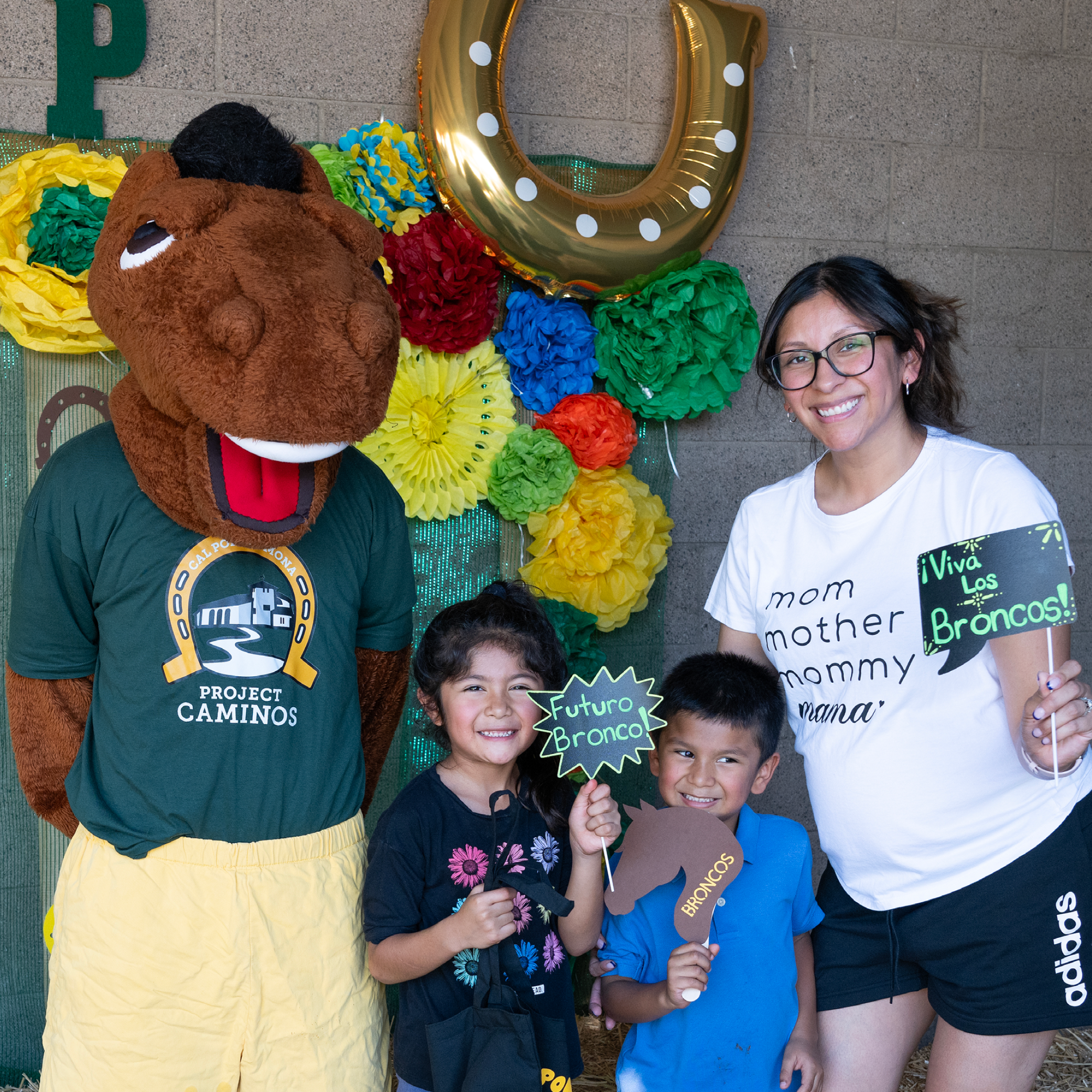 A student parent and her children pose with Billy Bronco