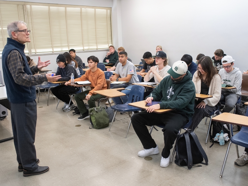 A teacher lectures to a full classroom.