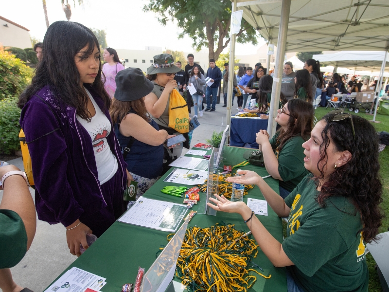 A student interacts with a staff member at a table during an outreach event.