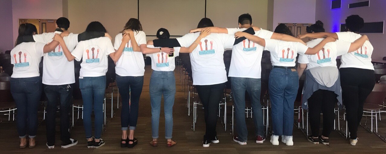 Students in a volunteer group show off their shirt artwork