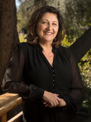 A professional woman in a black blouse is smiling at the camera. 