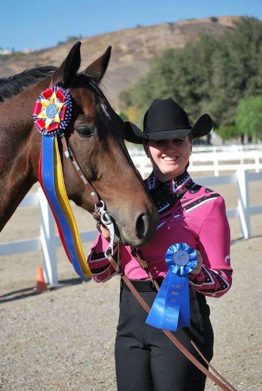 woman next to her horse with winning badges