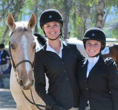 two equestrian women pose next to a horse icon