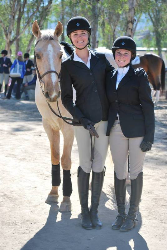two equestrian women pose next to a horse