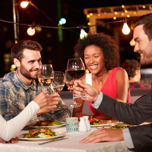 Dining and Wining - friends at dinner holding wine glass and toasting