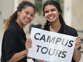 students holding tour sign