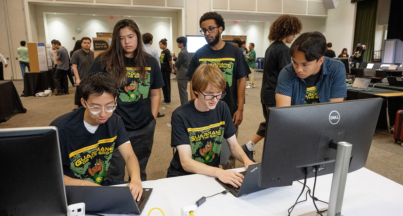 Students gathering in front of computer at Cybersecurity Fair
