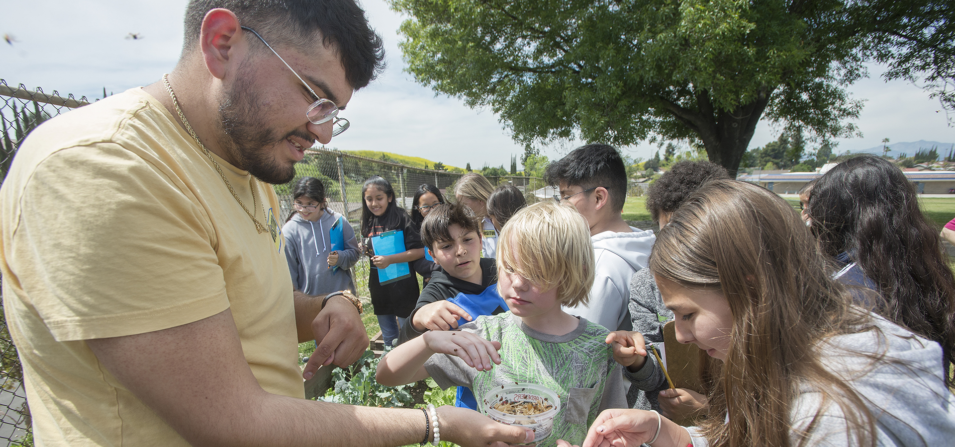 Martin Rios, a botany student and a Prete Fellow, shows a group of Armstrong Elementary students the loveliness of ladybugs that will be released into the garden.