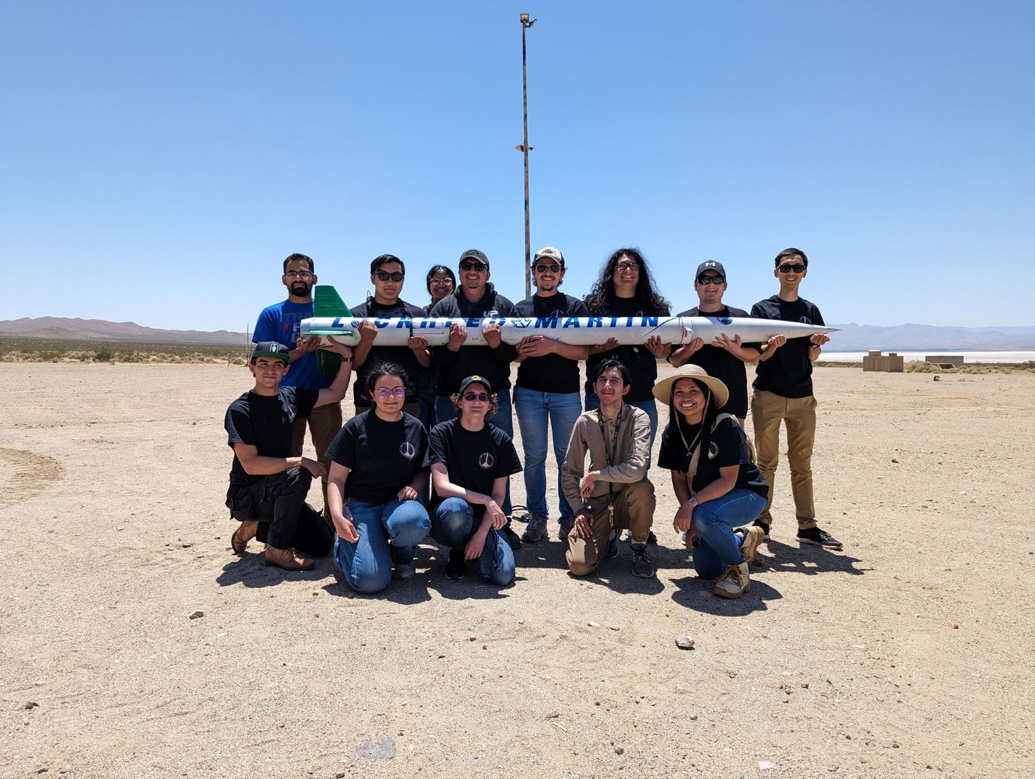 A group of Cal Poly Pomona engineering students with a large rocket they built and launched.