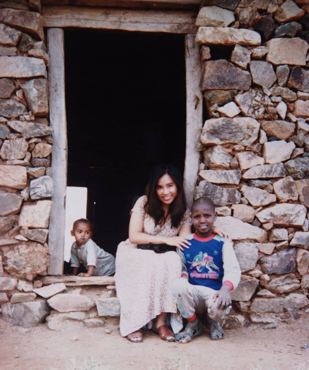 An old photo of a Vietnamese woman with a small child in an East African village.