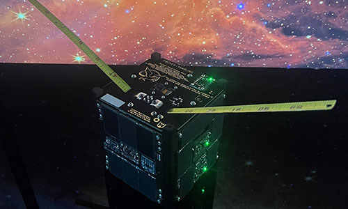 A photo of a CubeSat, a miniature satellite the size of a half-loaf of bread.