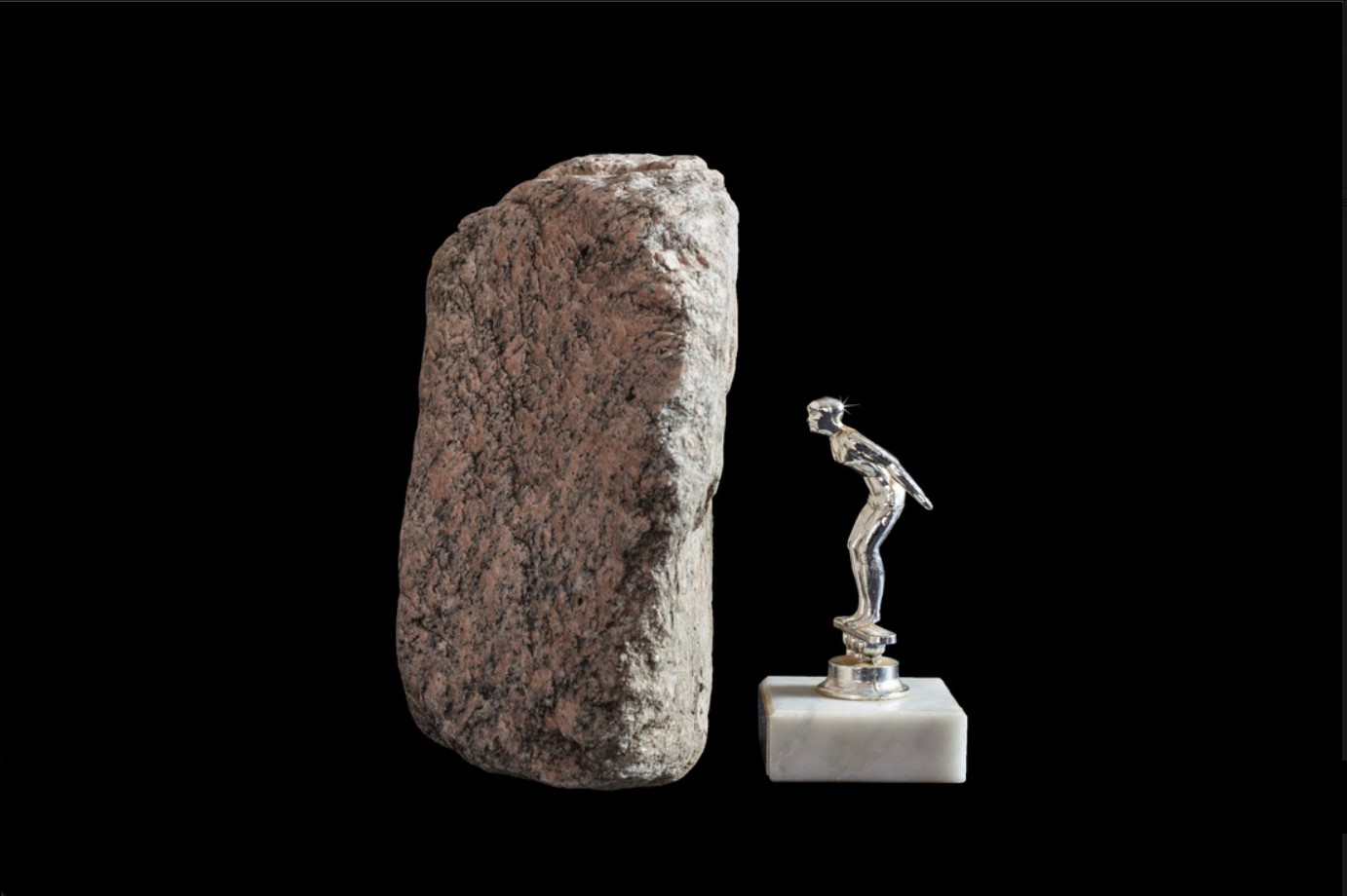 vertical rock next to a trophy of a man faced towards the rock